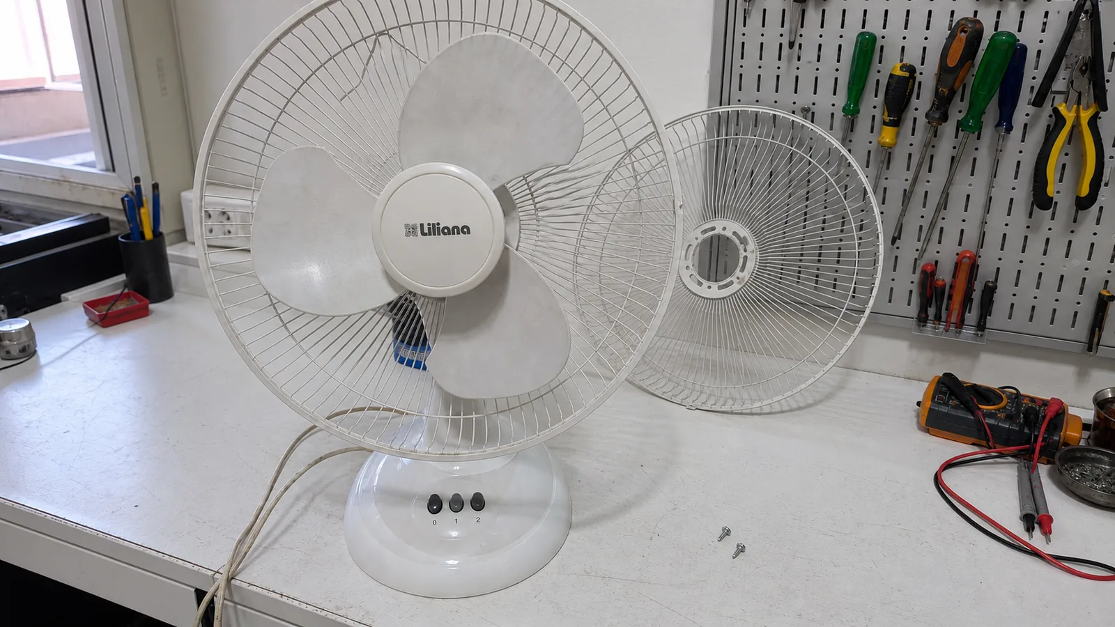 Ventilador Liliana sobre un banco blanco de reparación con su rejilla retirada